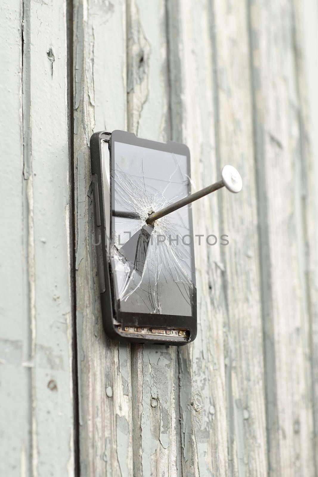 faulty mobile phone is nailed to an old fence by SmartPhotoLab
