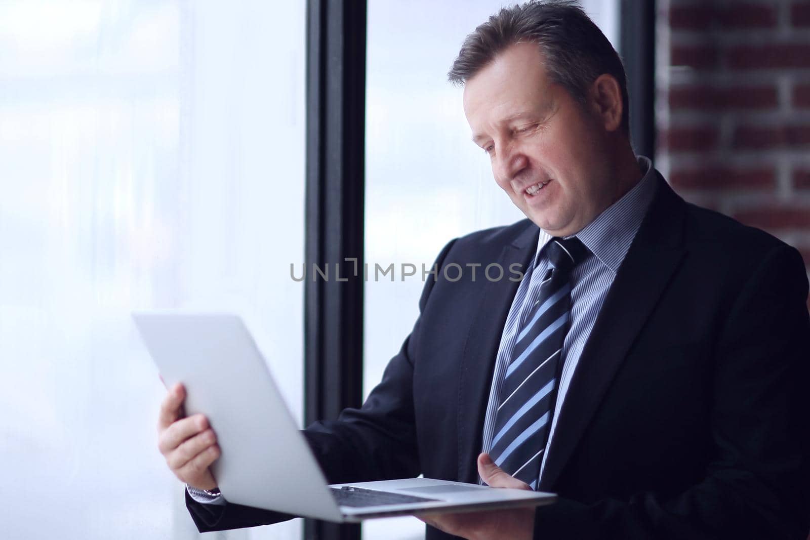 confident businessman with laptop standing in office.photo with copy space