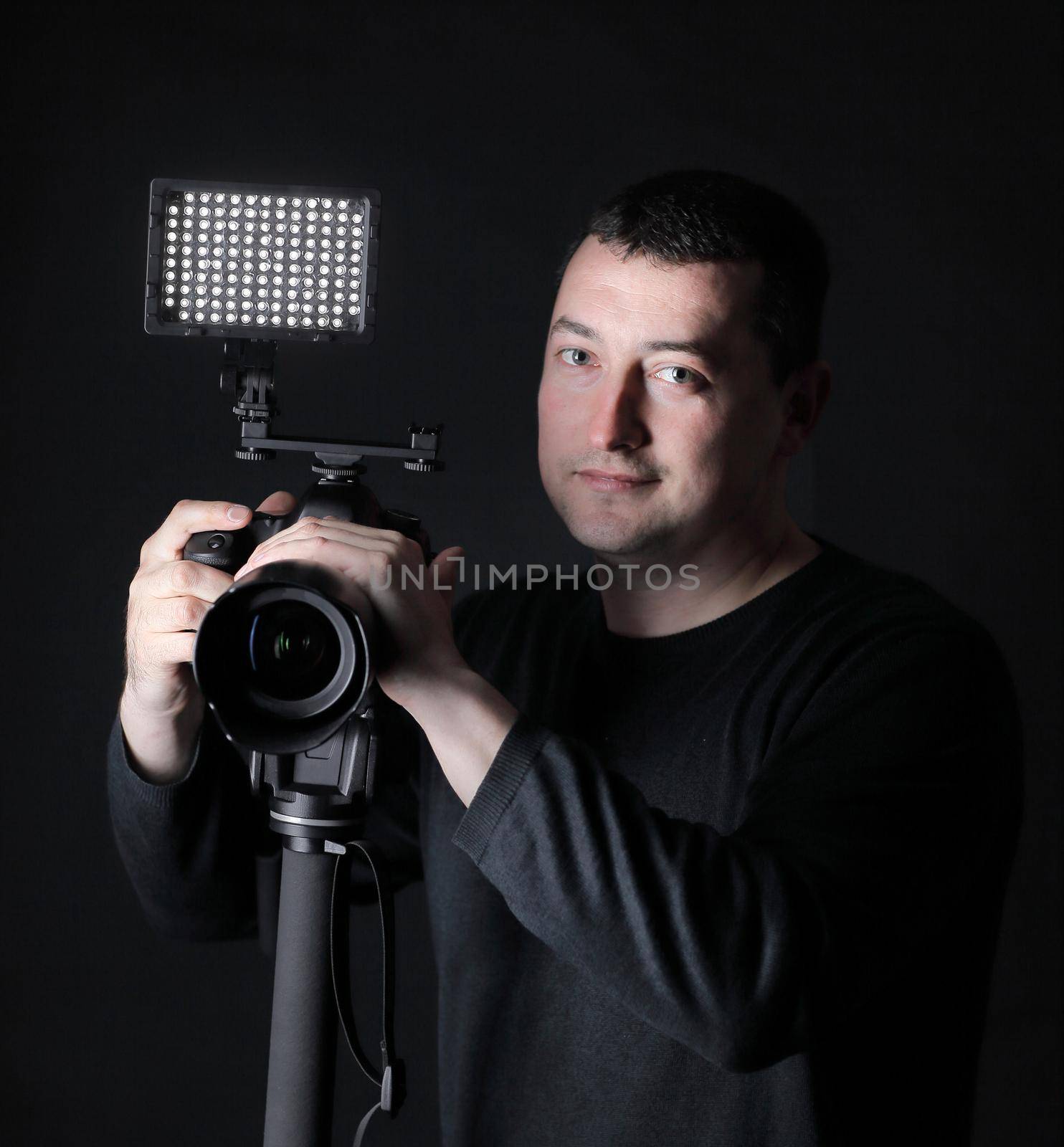 professional photographer with camera on tripod.isolated on black background.
