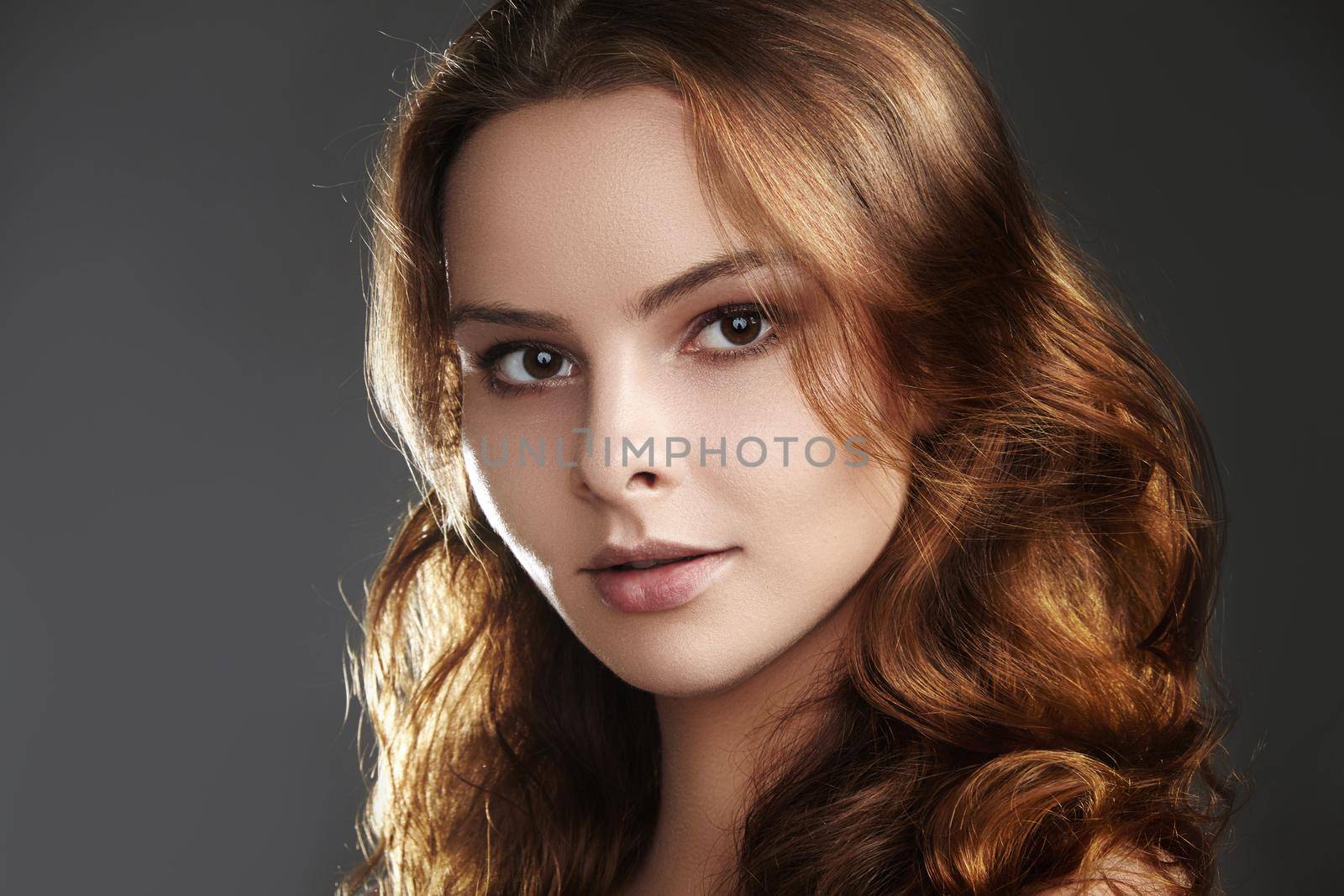 Beautiful young woman model with flying brown color hair. Beauty portrait with clean skin, glow glamour fashion makeup. Make up, curly hairstyle. Hair-care, make-up. Horizontal beauty portrait