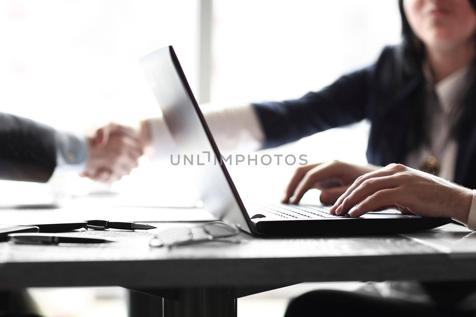 close up.businessman working on laptop on the background of handshake of business partners