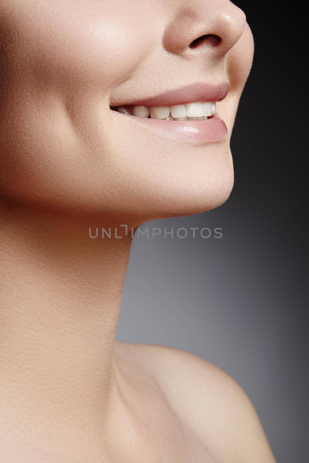 Wide smile of young beautiful woman with perfect healthy white teeth on grey background. Dental whitening, ortodont, care tooth and wellness.