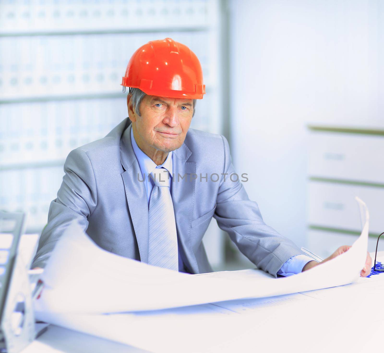 Engineer at the age of considering plans drawing and corrects them.