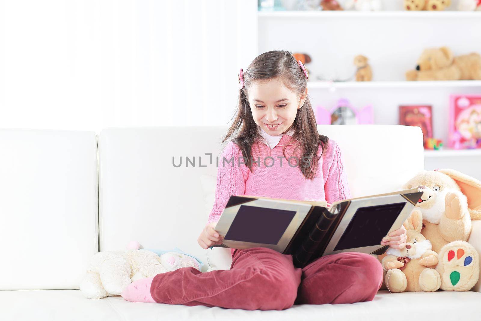 girl reading a book sitting on the couch in the nursery by SmartPhotoLab