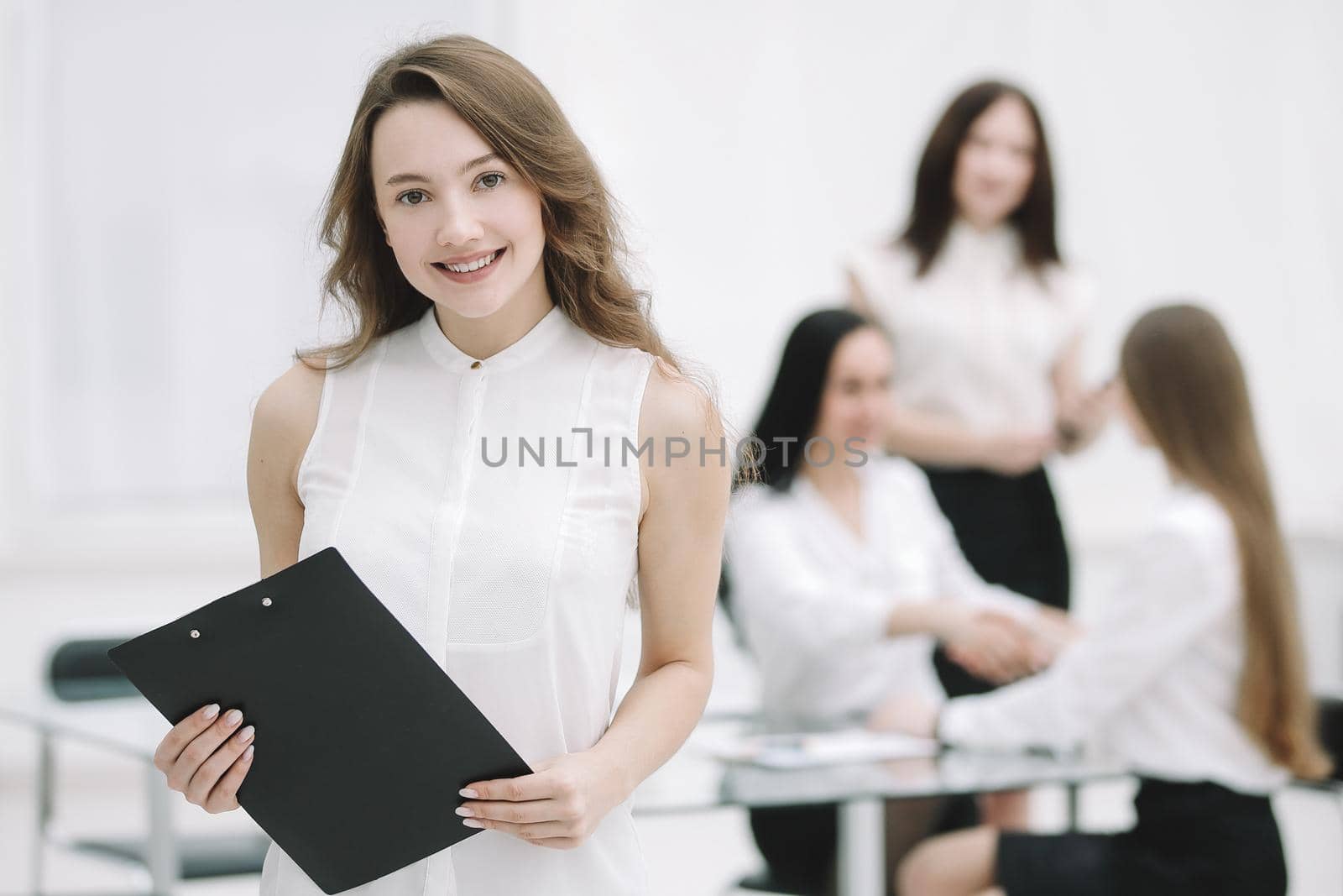successful young business woman with clipboard in the background of the office.