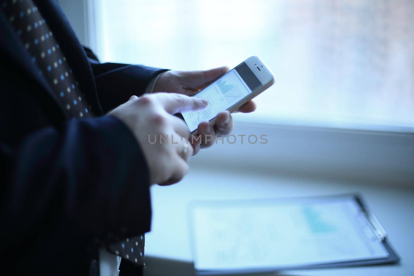 close up. a businessman uses a smartphone while standing near a work table in the office.photo with copy space