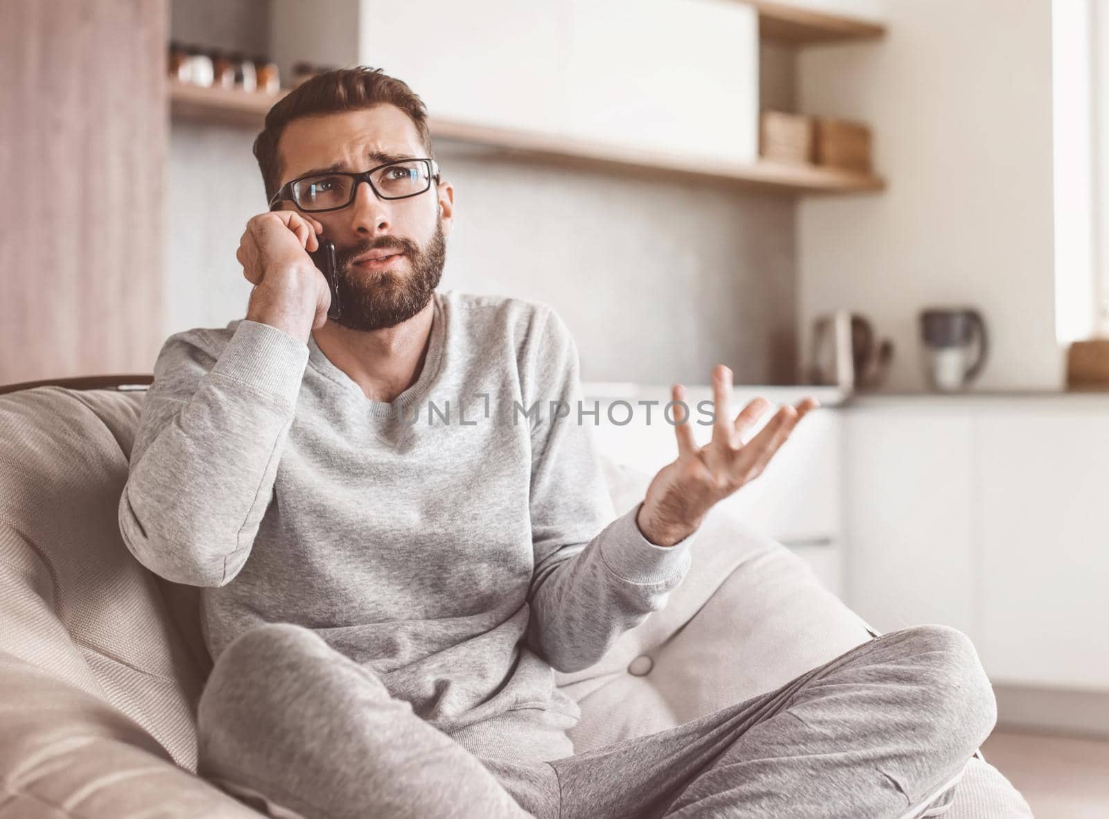cheerful man talking on a mobile phone sitting in a comfortable chair by asdf