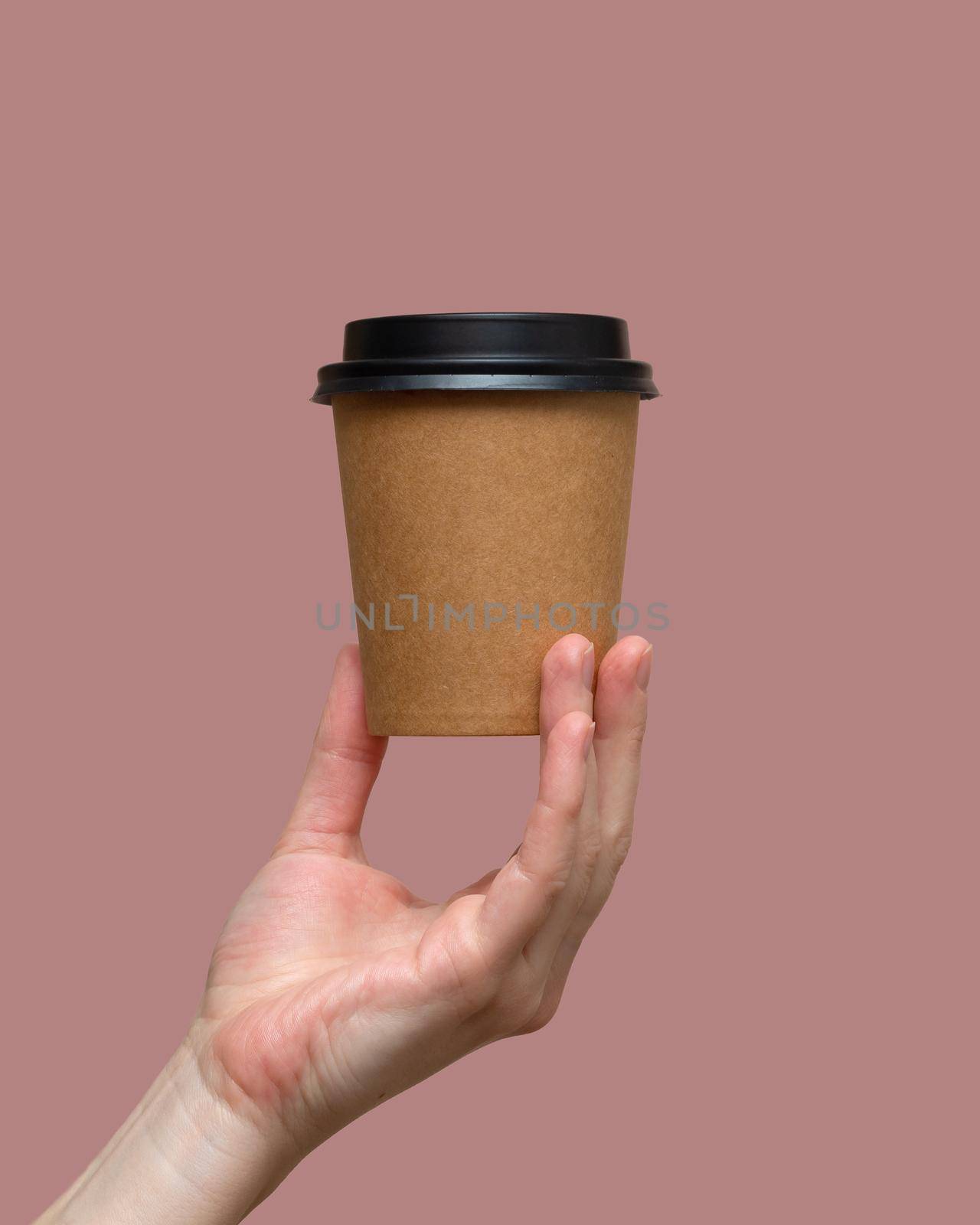 Woman hands hold paper cup on pink background. Copy space. photo
