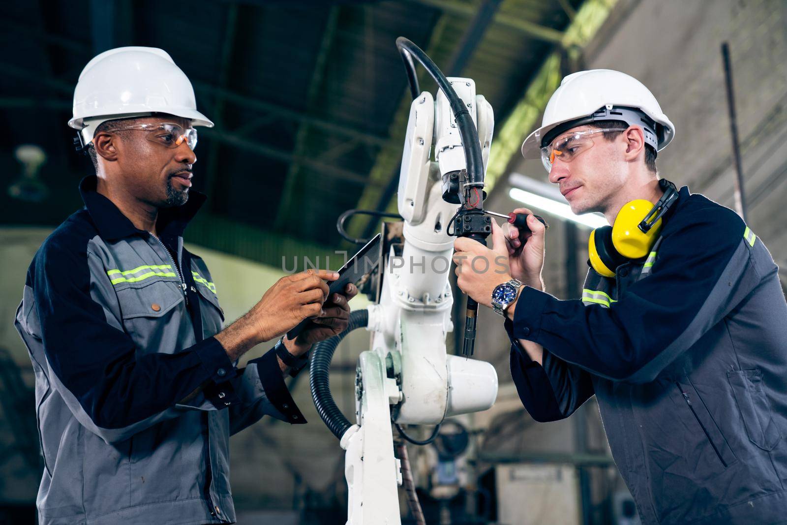 Factory workers working with adept robotic arm in a workshop . Industry robot programming software for automated manufacturing technology .