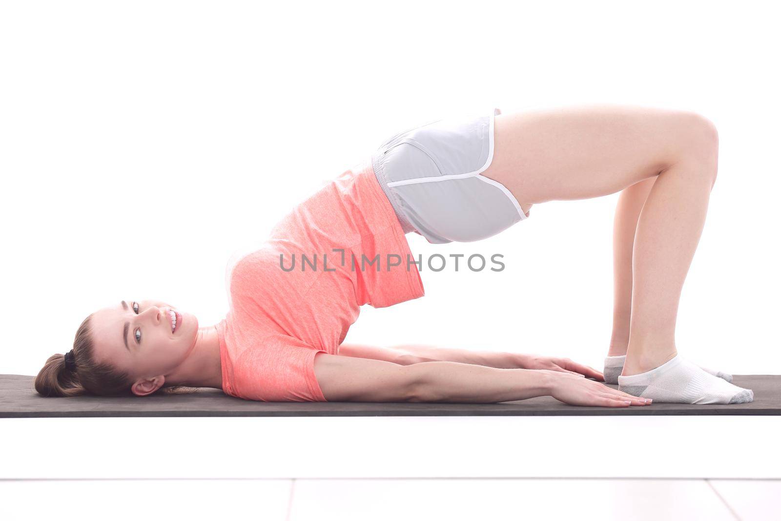 Side view of young woman doing gymnastics the half bridge pose.