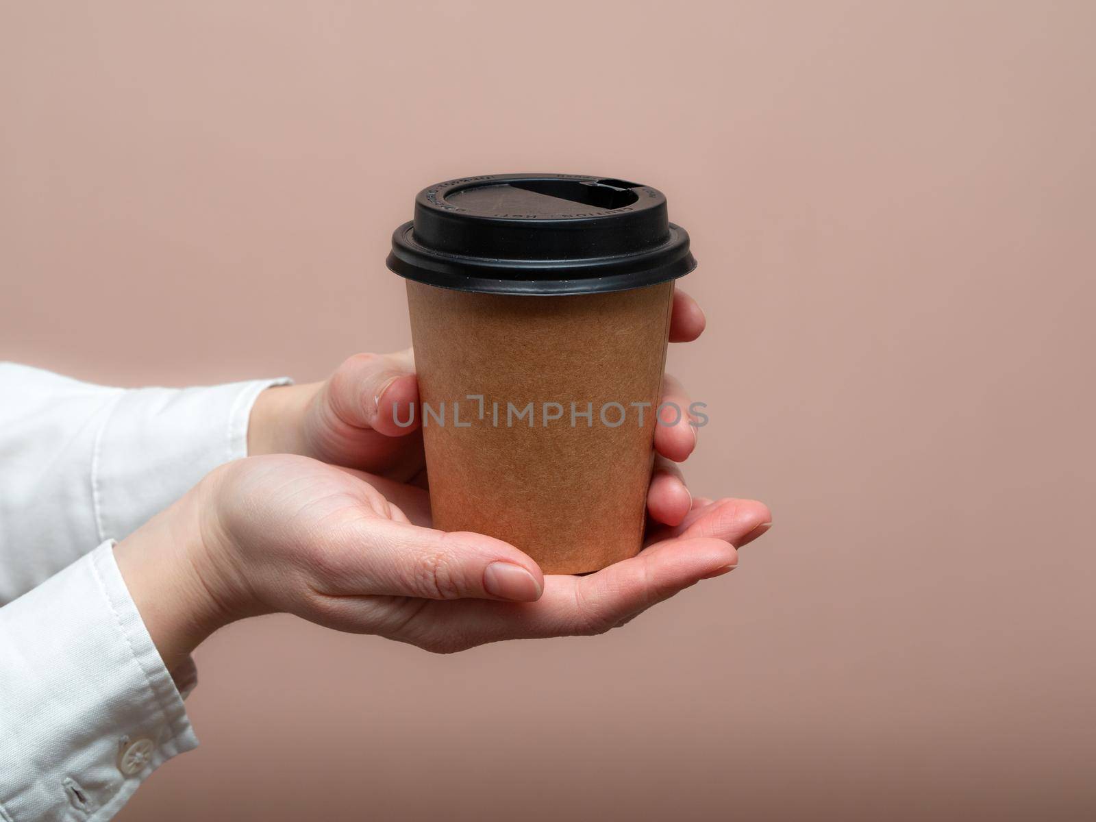 Woman hands hold paper cup on pink background. Copy space. photo