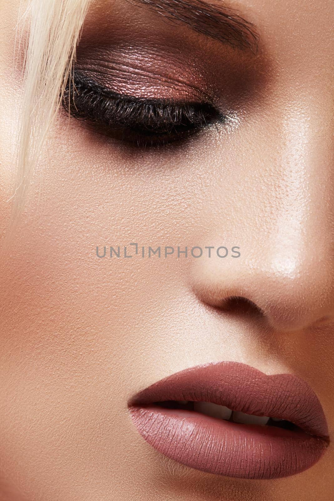 Closeup portrait with of beautiful woman face. Fashion makeup, clean shiny skin. Makeup and cosmetic. Beauty style on model face. Blond hair style