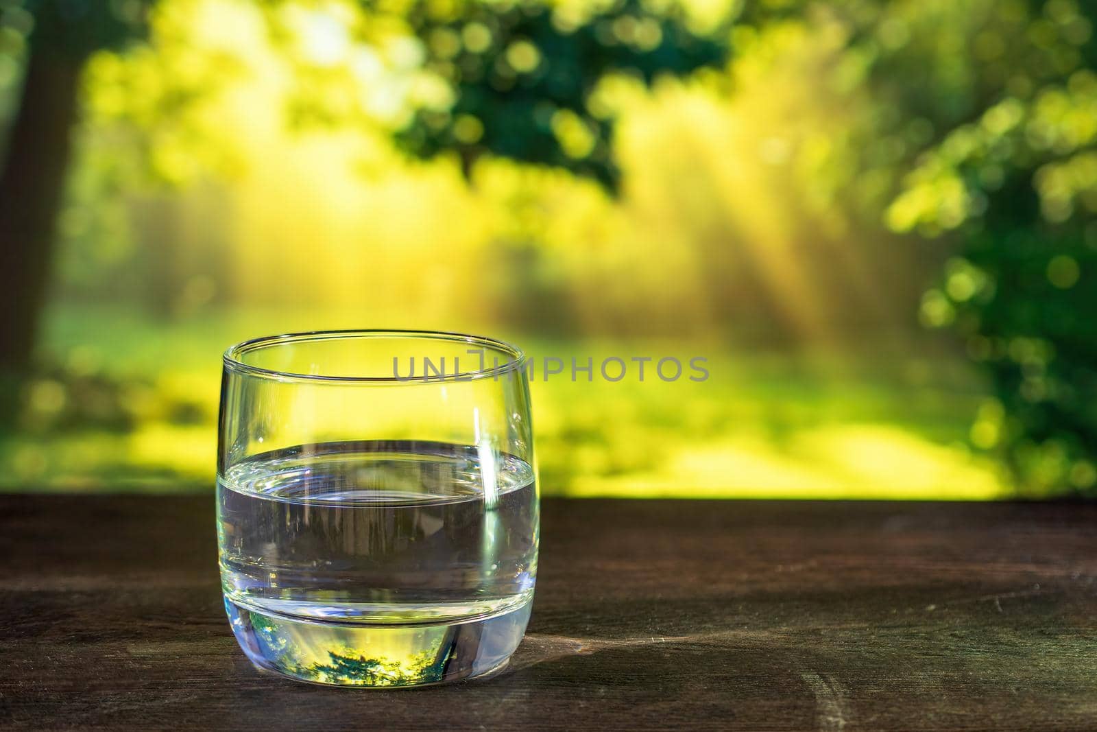 closeup water pouring into glass on green blurred background. photo