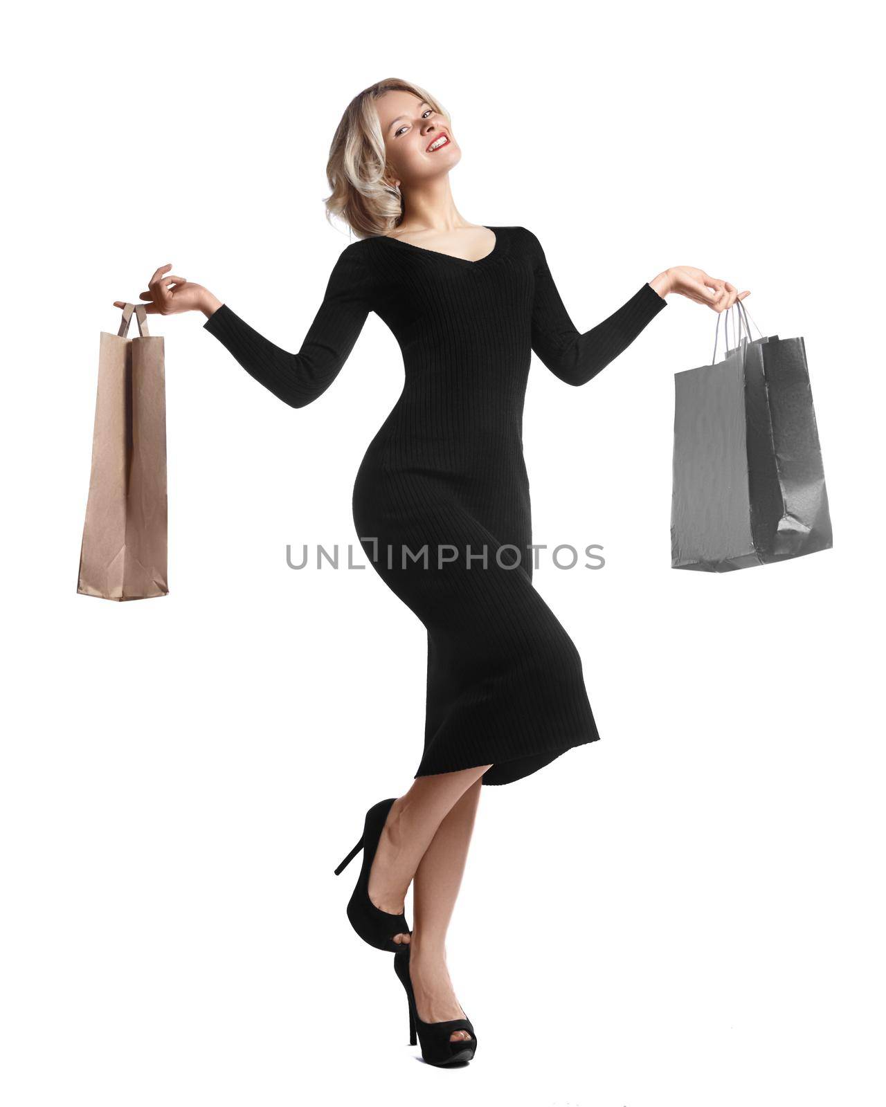 Shopping young woman holding bags isolated on white studio background. Love fashion and sales. Happy blond girl in black luxury glomour dress, shopper with handbags and gifts.