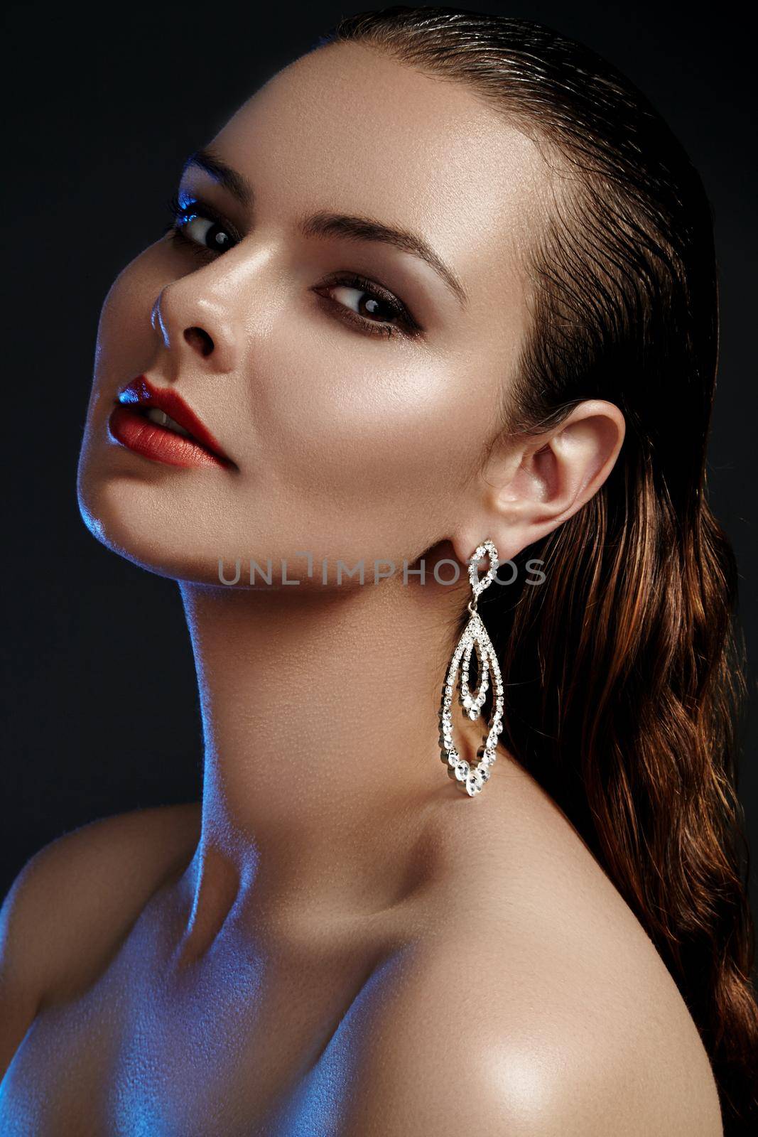 Beautiful woman in luxury fashion earrings. Diamond shiny jewelry with brilliants. Sexy retro style portrait. Model with glamour accessories jewelery, fashion makeup, clean shiny skin and wet hair