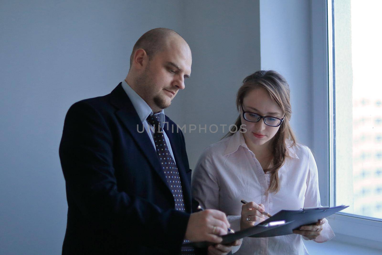 surprised businessman and assistant discussing business documents by SmartPhotoLab