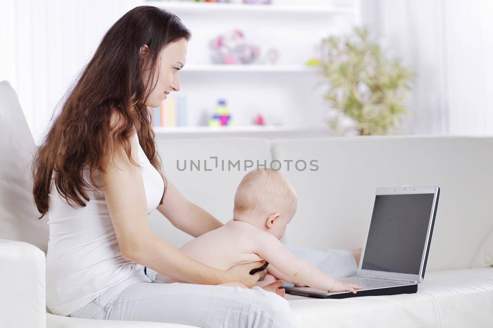 young mother plays with the baby and talking on a mobile phone by SmartPhotoLab