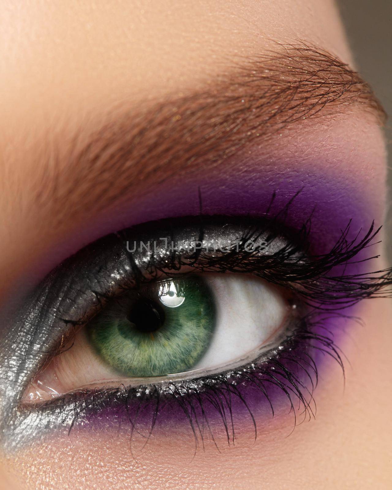 Closeup female eye with fashion bright make-up. Beautiful silver, purple eyeshadow, glitter, black eyeliner by MarinaFrost