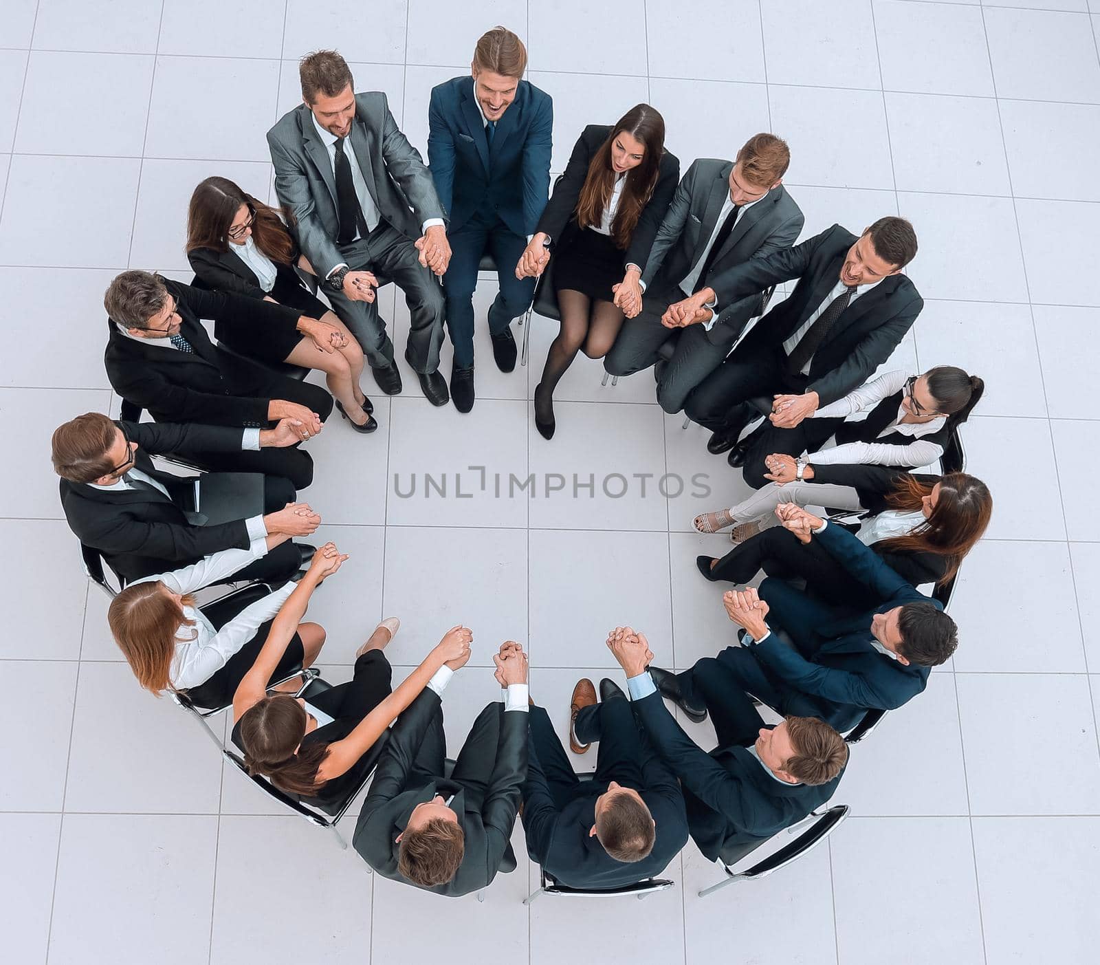 concept of team building.large business team sitting in a circle and holding each other's hands