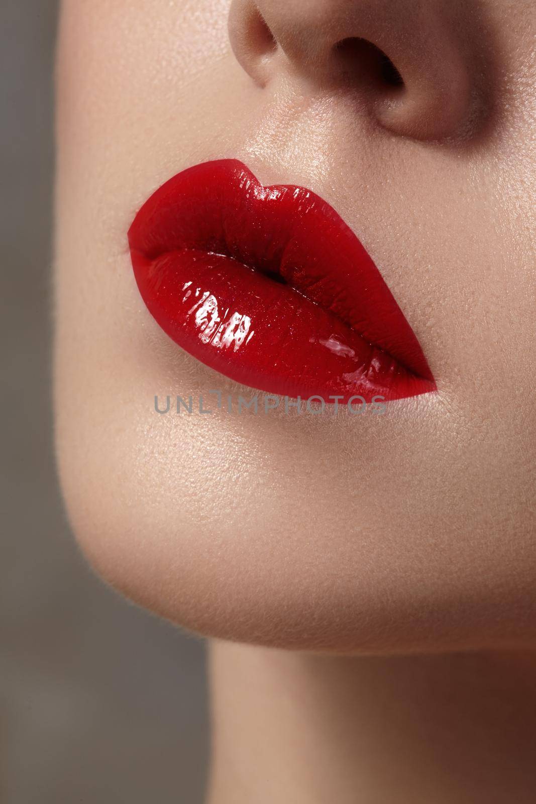 Close-up of female lips with bright makeup. Macro of woman's face. Fashion lip make-up with red gloss.Red lipgloss makeup on full female lips