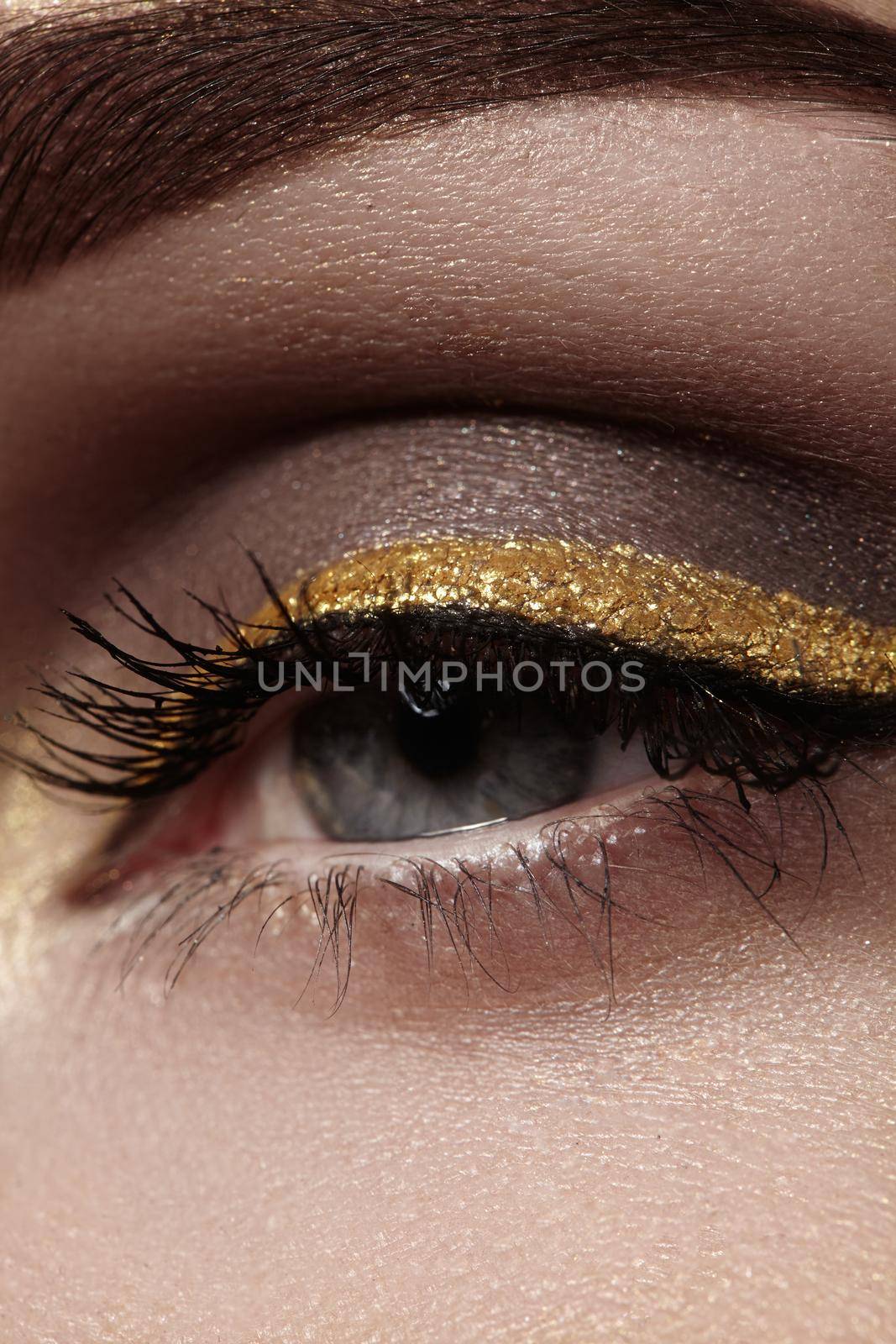 Beautiful macro shot of female eye with ceremonial makeup. Perfect shape of eyebrows, eyeliner and gold line on eyelid by MarinaFrost