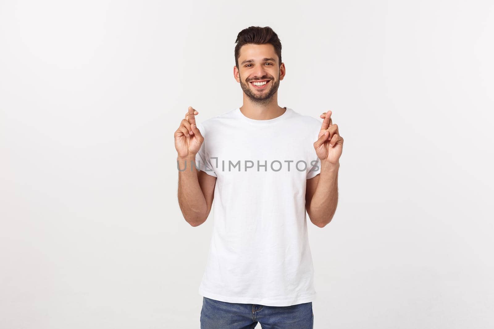 Closeup portrait of young handsome man crossing fingers, wishing, praying for miracle, hoping for the best, isolated on white background