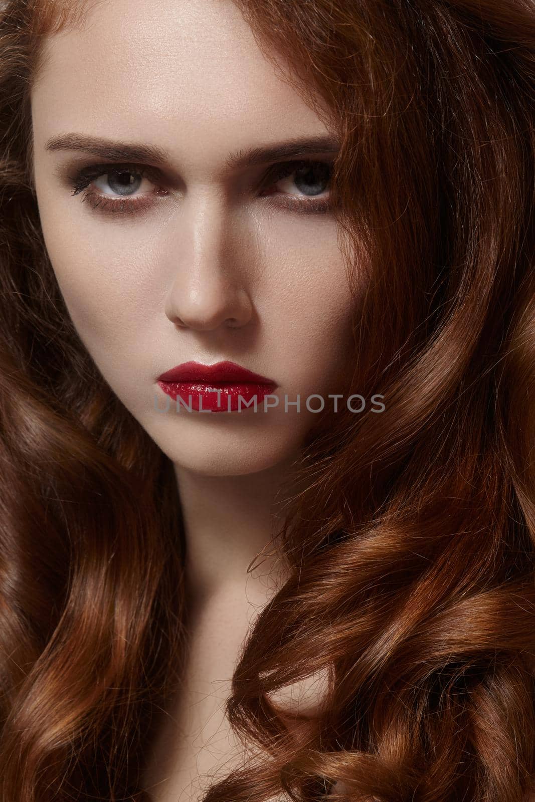 Beautiful ginger young woman with luxury hair style and fashion gloss makeup. Beauty portrait of sexy model with red hair. Long soft shiny hairstyle. Close-up studio shot of look redhead girl