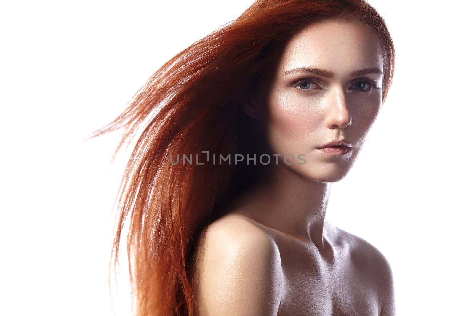 Beautiful ginger young woman with flying hair and naturel makeup. Beauty portrait of sexy model with straight red hair. Long soft shiny hairstyle. Close-up studio shot o fashion look redhead girl