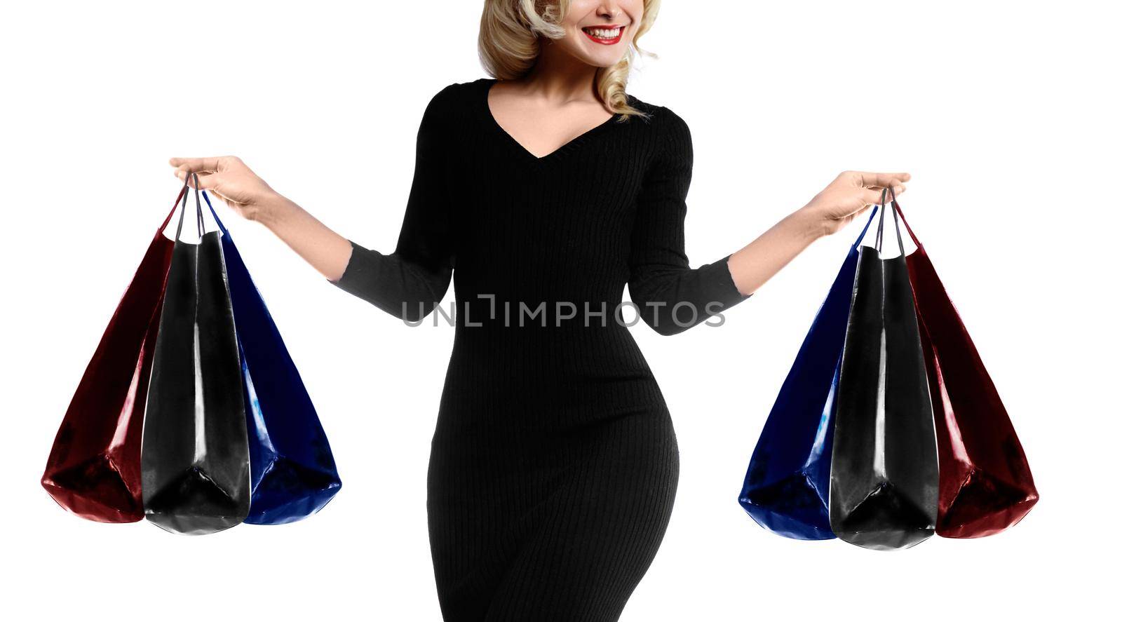 Shopping young woman holding bags isolated on white studio background. Love fashion and sales. Happy blond girl in black luxury glomour dress, shopper with handbags and gifts.