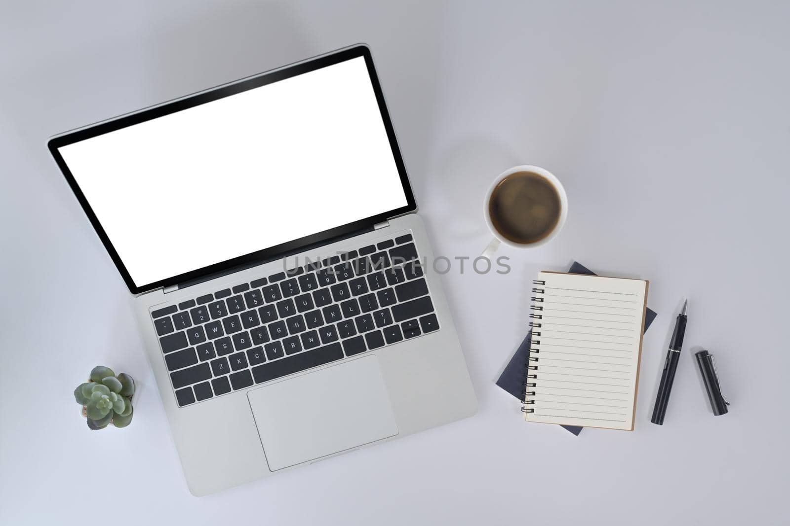 Laptop computer, notebook and coffee cup on white office desk. Top view.