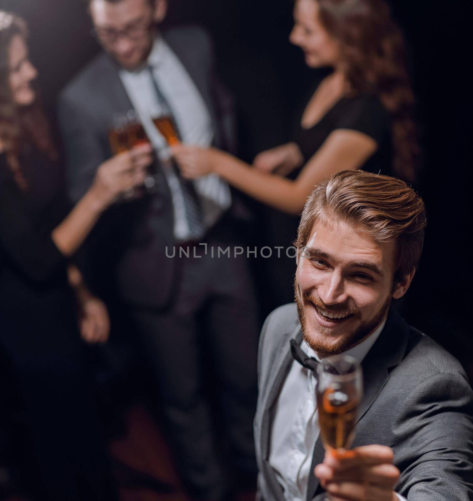 stylish young man standing with a glass of champagne. by asdf
