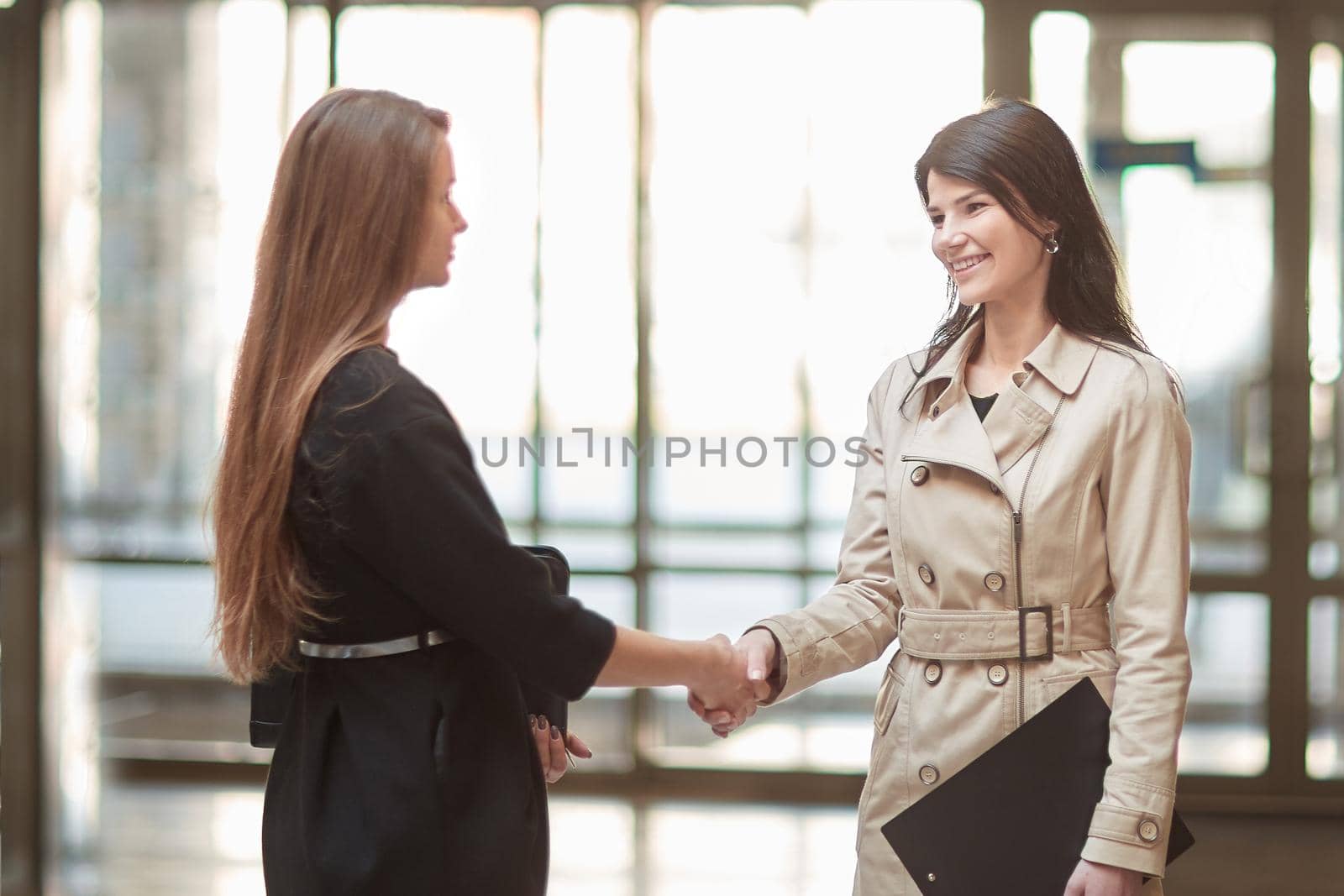 two businesswomen shaking hands in the office lobby. concept of partnership
