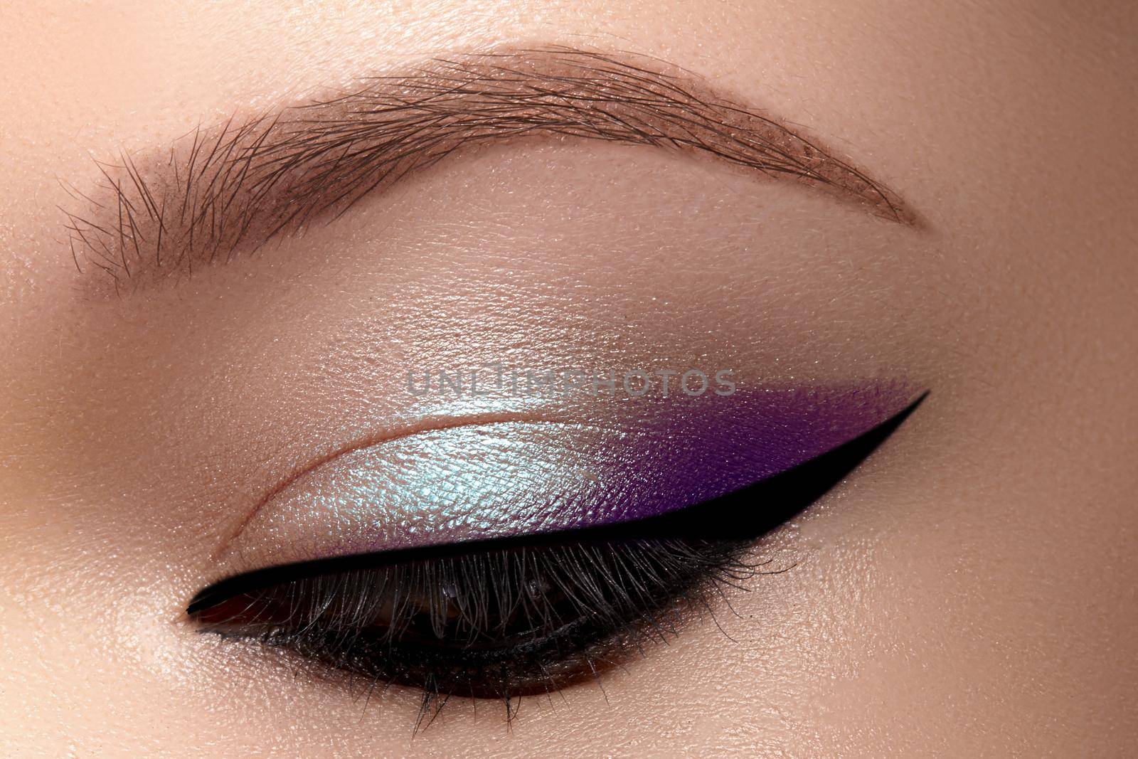 Celebrate Beautiful Macro Eyes with Smoky Cat Eye Makeup. Cosmetics and Make-up. Closeup of Fashion Visage with Liner, Purple and Cyan Eyeshadows.