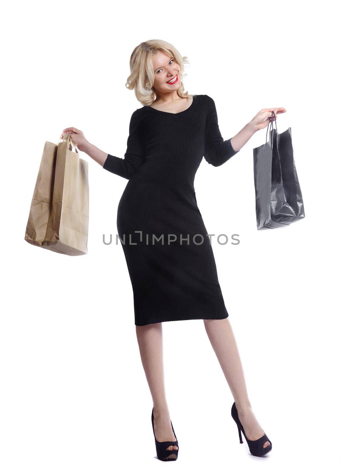 Shopping young woman holding bags isolated on white studio background. Love fashion and sales. Happy blond girl in black luxury glomour dress, shopper with handbags and gifts.