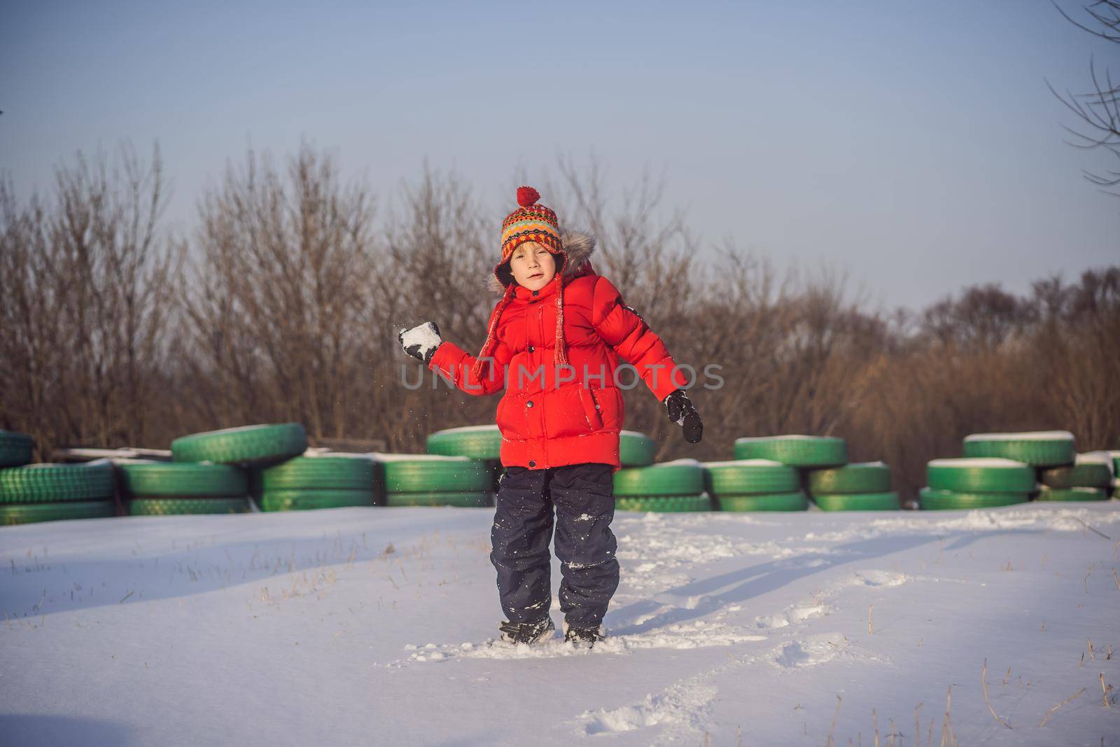 Boy in red fashion clothes playing outdoors. Active leisure with children in winter on cold days. Boy having fun with first snow. Happy little kid is playing in snow, good winter weather.