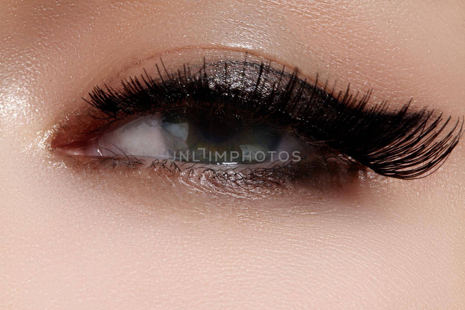 Beautiful macro shot of female eye with extreme long eyelashes and black liner makeup. Perfect shape make-up and long lashes. Cosmetics and make-up. Closeup macro shot of fashion eyes visage