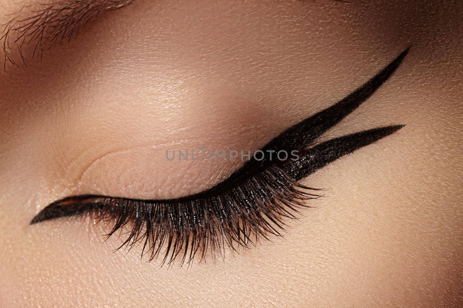 Beautiful macro shot of female eye with fashion black eyeliner makeup. Perfect graphic liner shape, minimalism style visage. Cosmetics and make-up. Closeup macro shot of fashion liner eyes visage