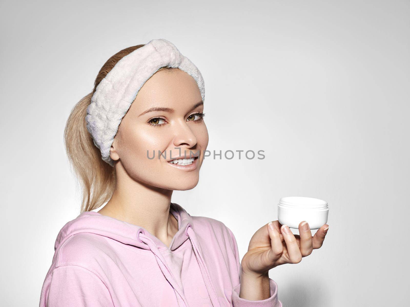 Happy woman with perfect skin applying day-night cream on cleansed face. Good concept of skincare, beauty industry, spa center and facial treatment