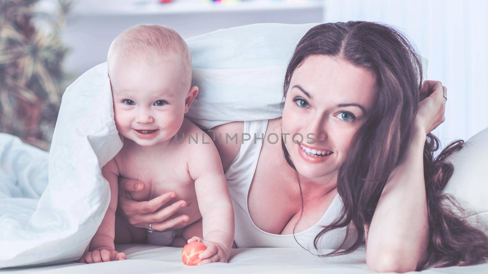 happy mother and her year-old child playing on the sofa in the bedroom