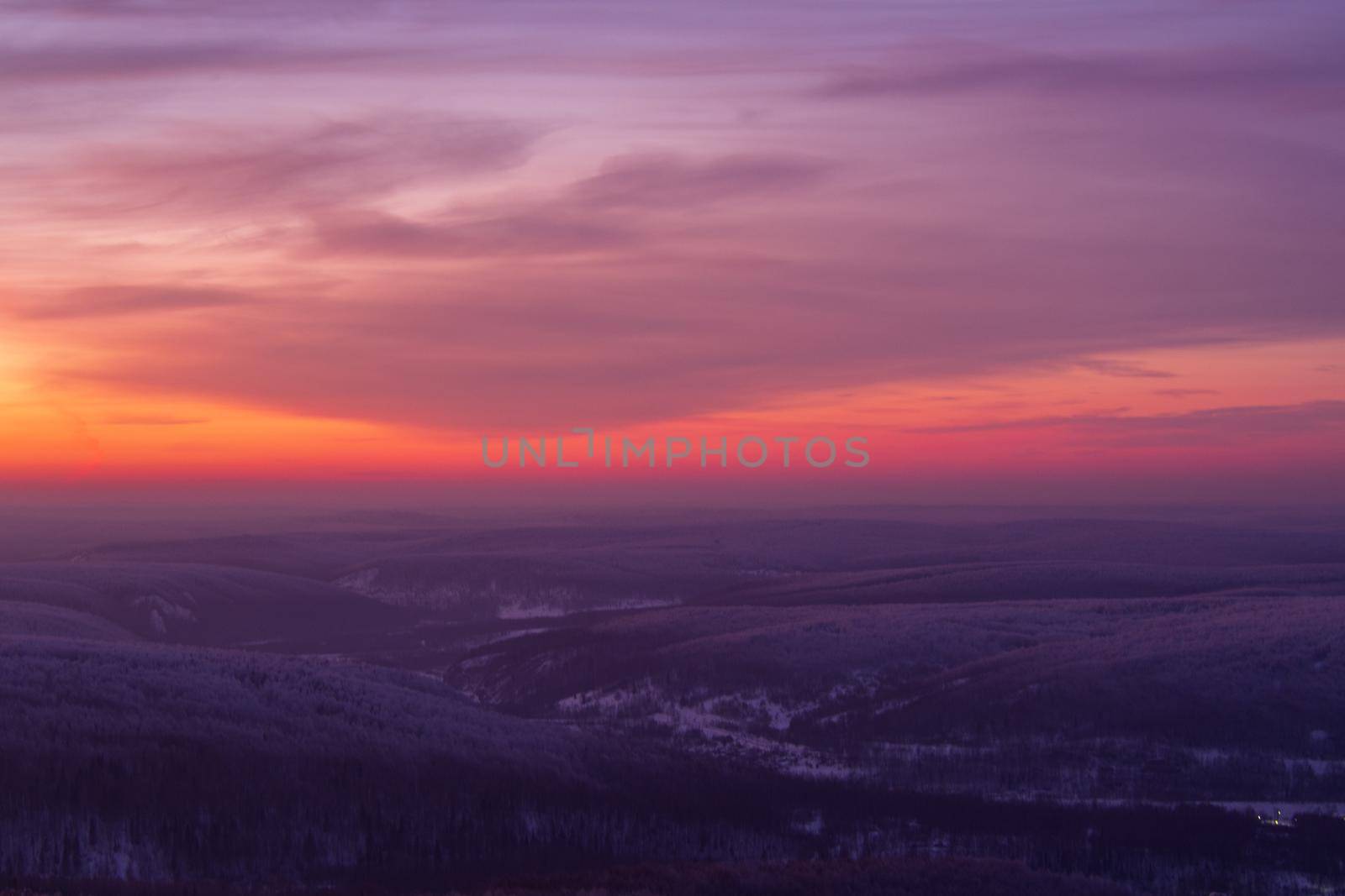 Epic red sunset over the rocks and stones of Ural mountains covered with snowy pines