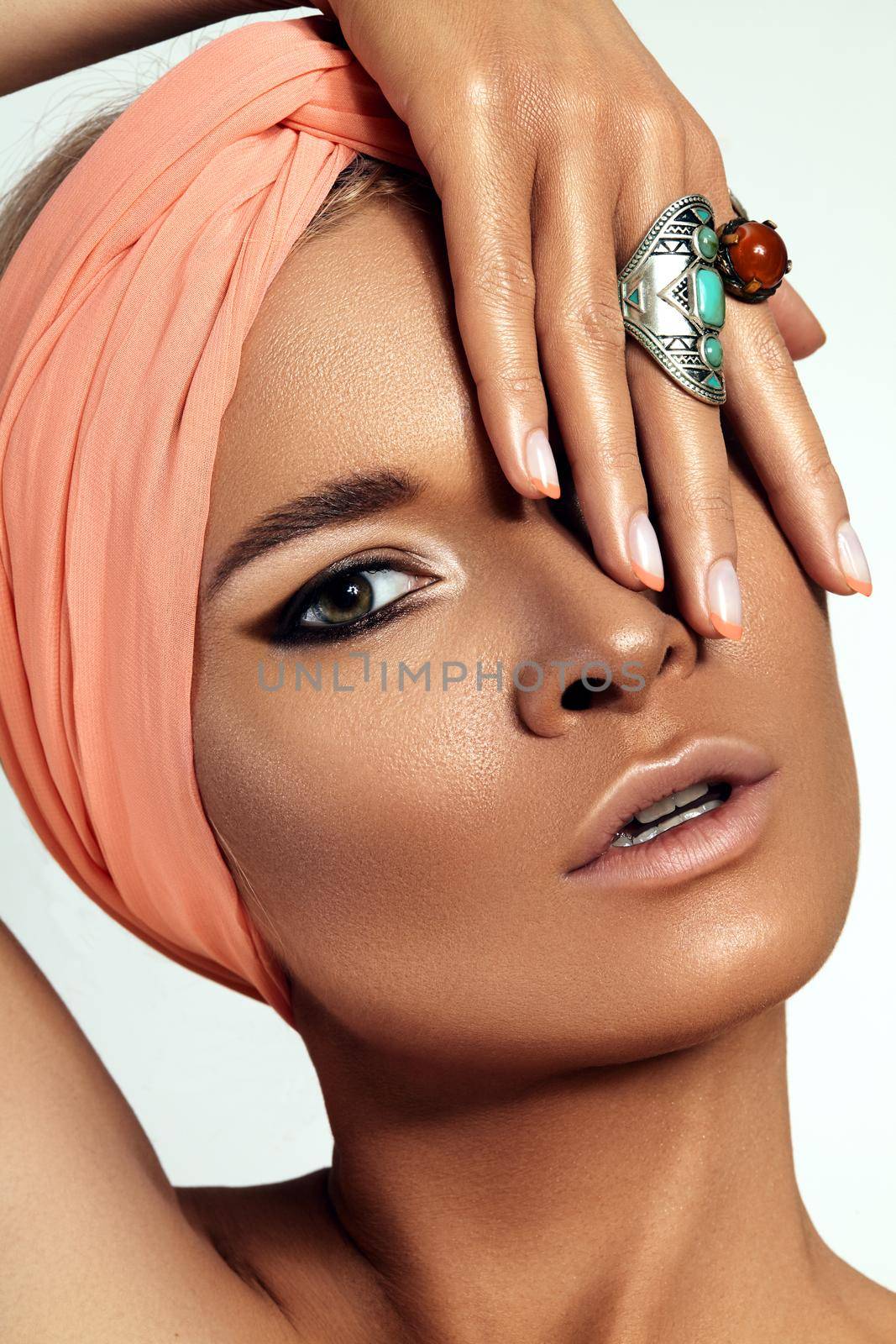 Beauty young Woman wearing Turban. Oriental Boho Style with Bohemian Accessories, Beautiful Rings, Fashion Make-up. Tanned Smooth Skin, Dark Arabian Makeup, Luxury Jewelry Rings and Perfect Manicure