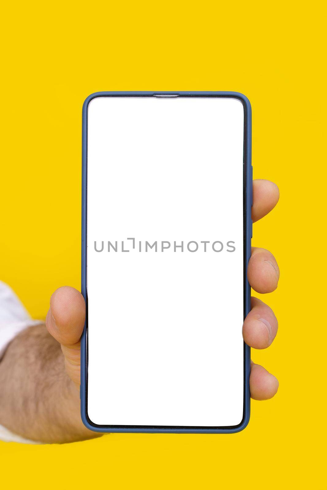 Close up man hand holding smartphone with white blank screen and blue phone case. Isolated on yellow background. Mobile phone frameless design concept for mobile app advertising. Copy space.