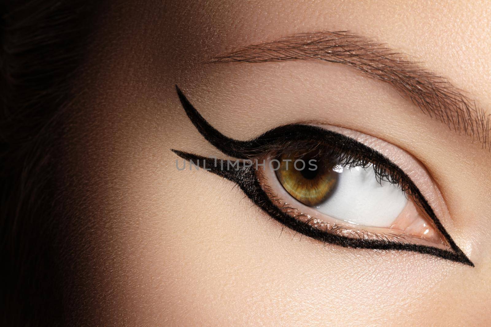 Beautiful macro shot of female eye with fashion black eyeliner makeup. Perfect graphic liner shape, minimalism style visage. Cosmetics and make-up. Closeup macro shot of fashion liner eyes visage