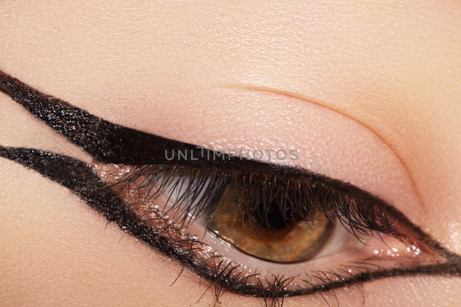 Beautiful macro shot of female eye with classic eyeliner makeup. Perfect shape of eyebrows, brown eyeshadows and long eyelashes. Cosmetics and make-up. Closeup macro shot of fashion liner eyes visage