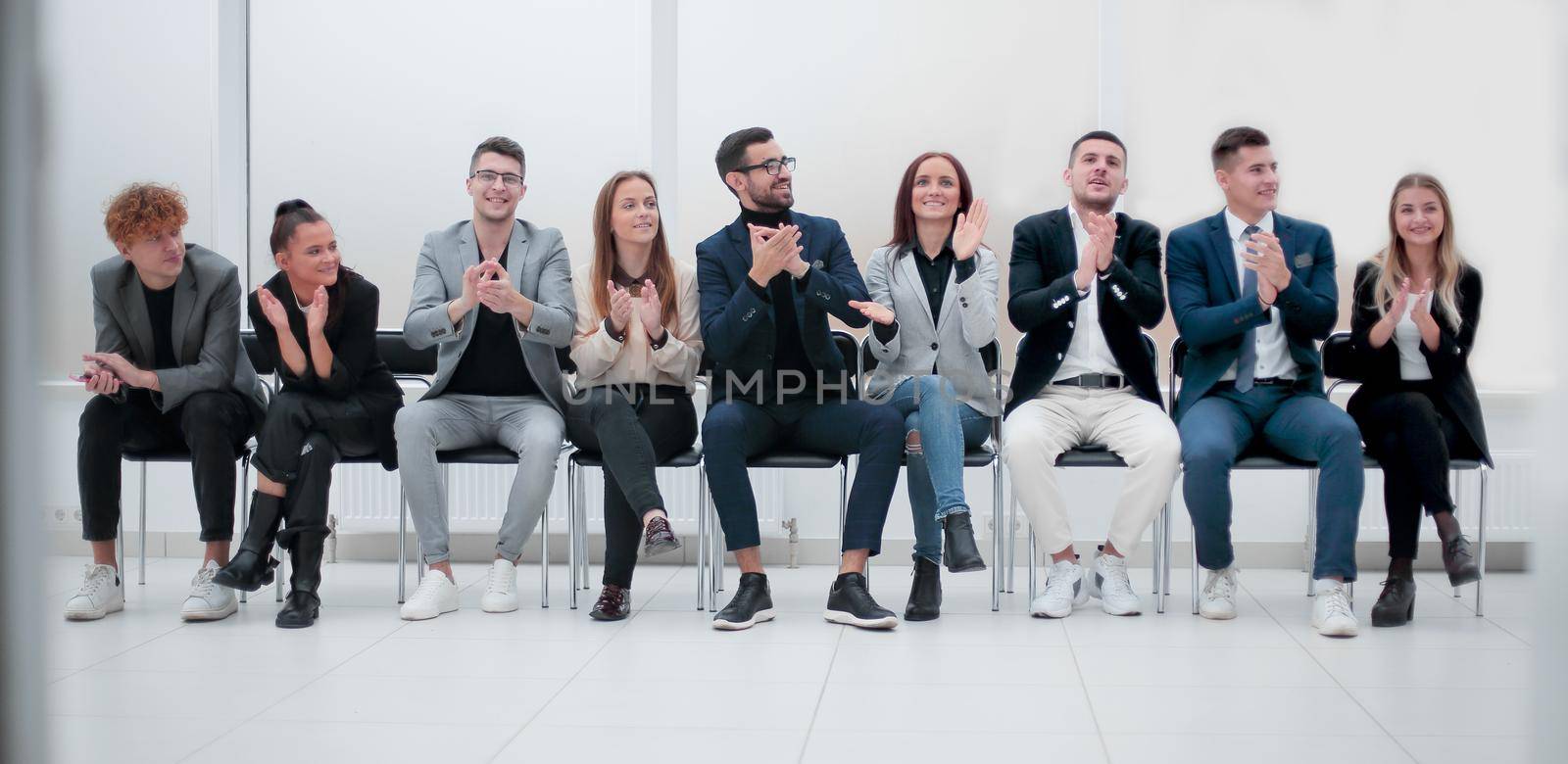 group of diverse business people applauding sitting in a row. by asdf