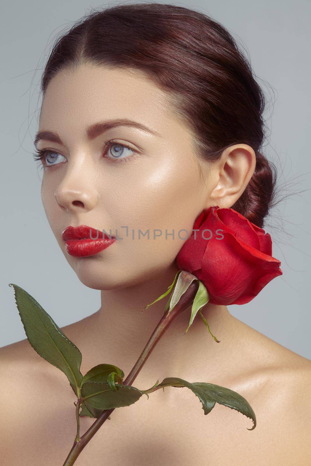 Close-up beautiful young woman with bright lipgloss makeup. Perfect clean skin, sexy red lip make-up. Beautiful valentine visage with red rose flower. Romantic and sexy look for Valentines day by MarinaFrost