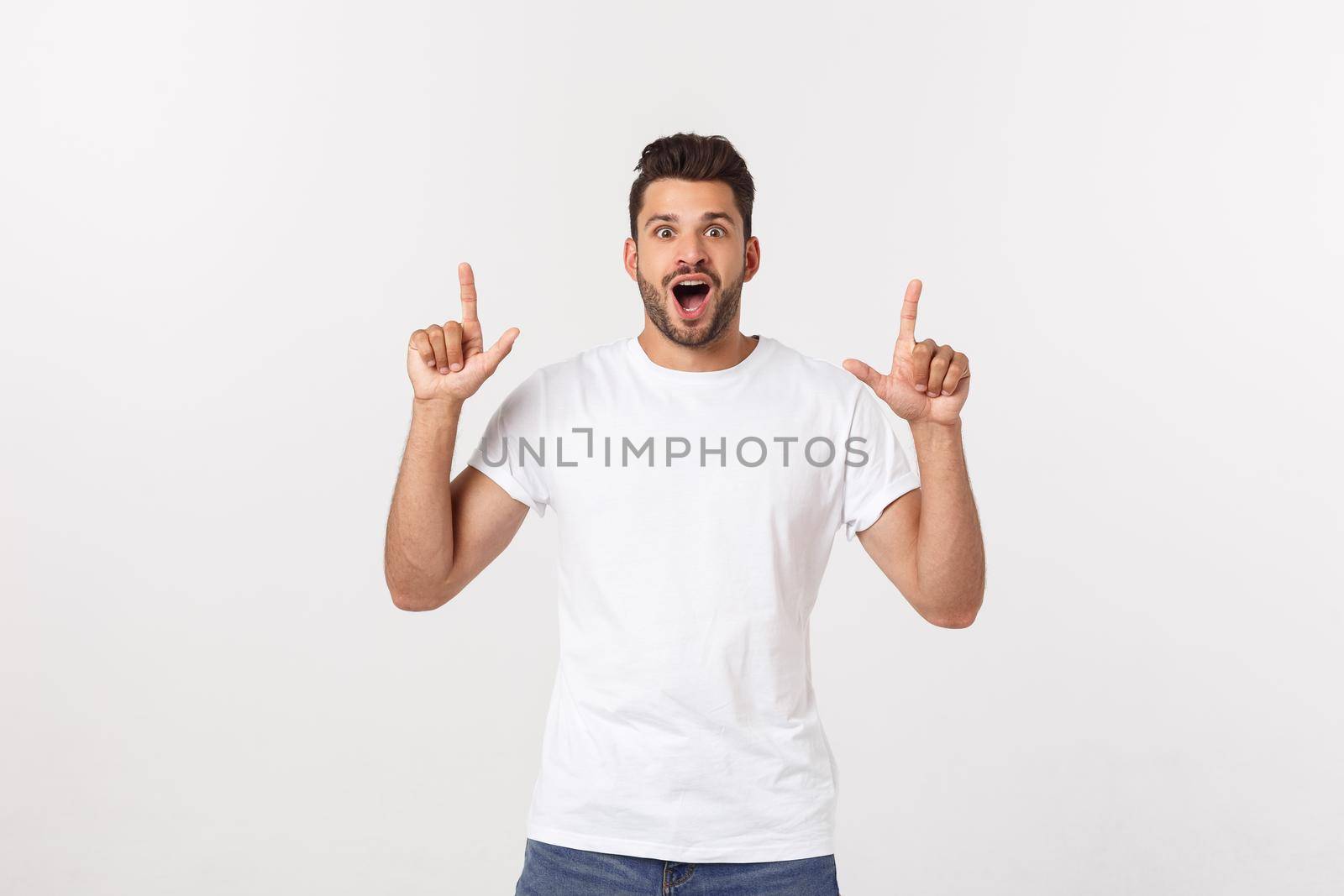 Portrait of an excited happy man pointing finger away at copy space. Isolated on yellow background