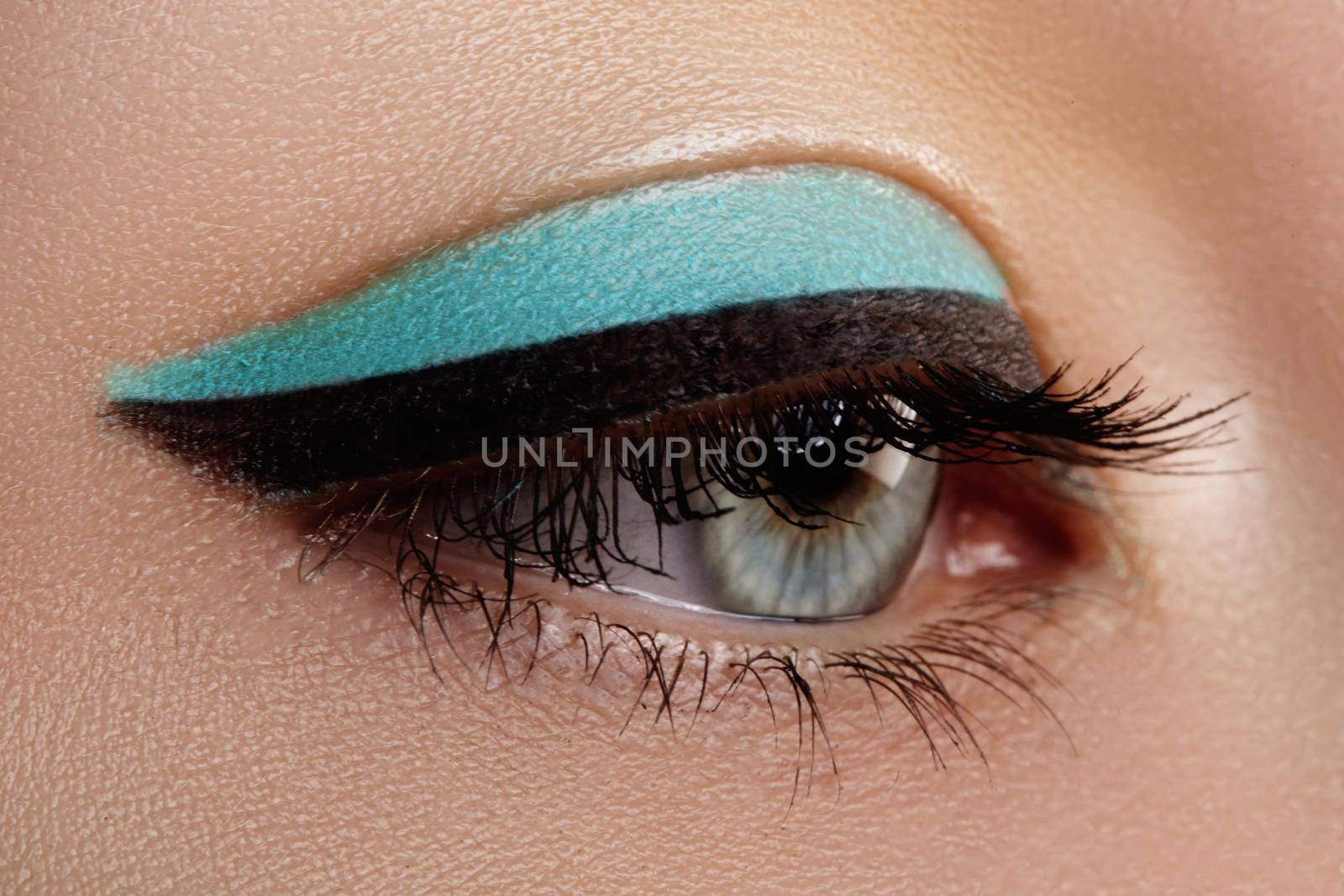 Beautiful macro shot of female eye with makeup. Perfect shape of eyebrows, blue eyeliner. Cosmetics and make-up.