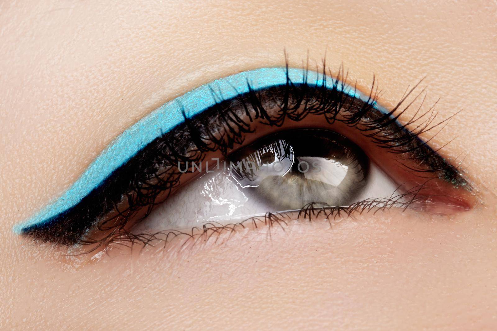 Beautiful macro shot of female eye with makeup. Perfect shape of eyebrows, blue eyeliner. Cosmetics and make-up.