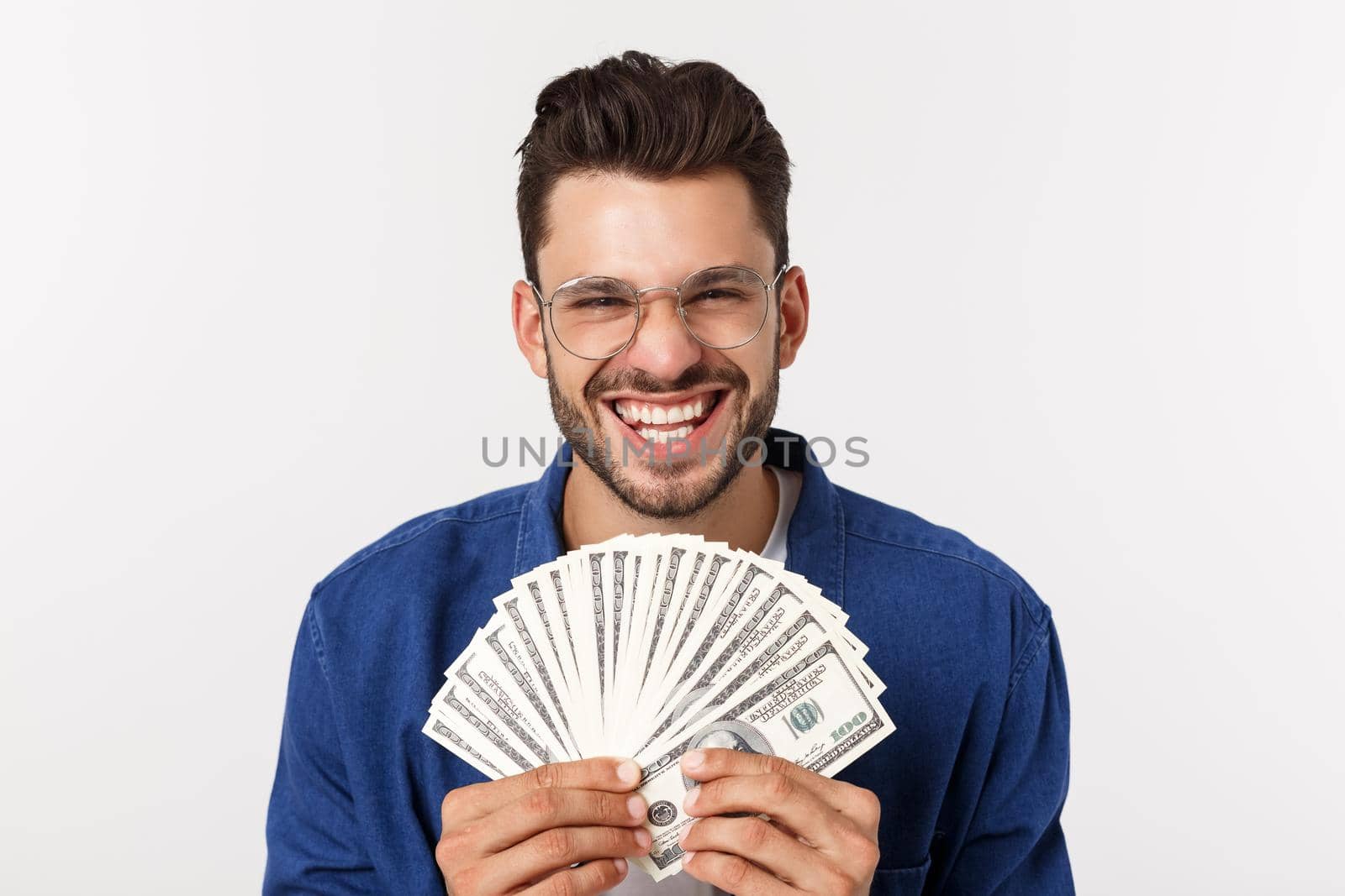 Attractive man is holding cash money in one hand, on isolated white background by Benzoix